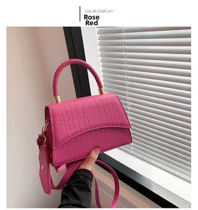 Détail du sac à main rose rouge à motif crocodile avec poignée tressée et dorures