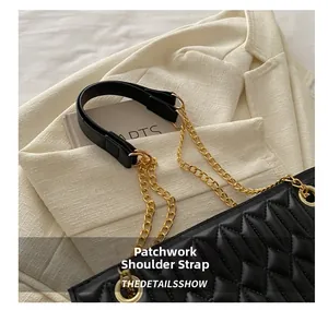 Detail of a quilted black shoulder bag featuring a gold chain and leather patchwork strap