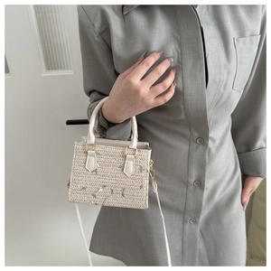 Détail d'un sac à main en paille avec broderies florales et poignées blanches