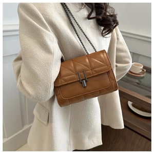 Détail d'un sac à bandoulière matelassé caramel avec chaîne et fermoir en métal chic