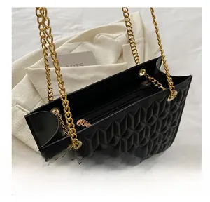 Detail showing black quilted tote bag with diamond stitching and golden chain straps