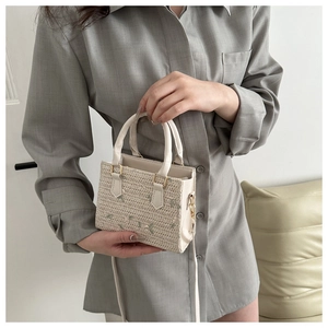 Détail du sac à main en paille avec broderie florale et poignée en simili cuir blanc