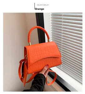 Détail d'un sac à main orange motif crocodile avec poignée tressée et finitions dorées