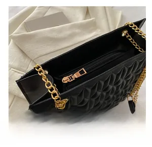 Detail view of smooth golden metal zipper and quilted texture on black crossbody bag