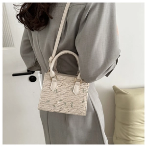 Détail du sac à main en paille crème avec broderie florale et bandoulière réglable