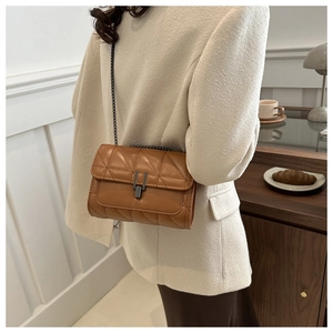 Gros plan d'un sac en cuir matelassé marron avec motifs en losange et chaîne métallique