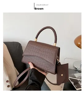 Détail du sac à main marron motif crocodile avec poignée tressée et finitions dorées chic