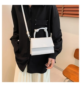 Detailed view of white crossbody bag with textured leather and unique knotted top handle