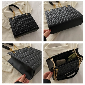 Detail of black geometric quilted tote bag with gold chain strap and spacious interior