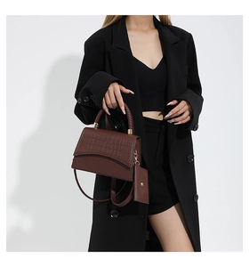 Détail d'un sac à main marron foncé aspect crocodile avec poignée tressée et petit porte-monnaie