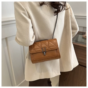 Détail du sac bandoulière en cuir caramel avec motif matelassé et bandoulière chaîne