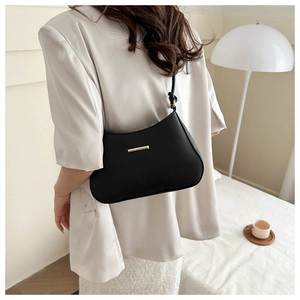 Detail of a black matte leather hobo bag with gold metal trim on a white blazer