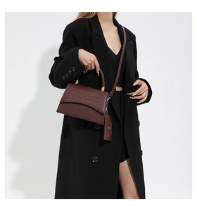 Détail du sac bandoulière marron foncé motif crocodile avec poignée tressée et pochette