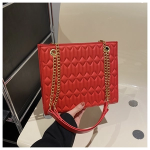 Close-up of red quilted leather texture with gold metal chain strap on shoulder bag
