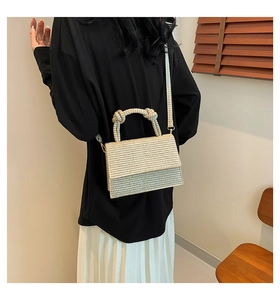 Detail of woven texture flap square bag with a knotted top handle and beige shoulder strap
