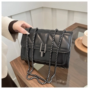 Détail du sac matelassé noir avec bandoulière chaîne, fermoir en H et cuir brillant