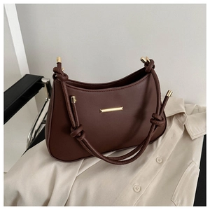 Detailed view of dark brown matte leather shoulder bag with gold hardware and knot strap