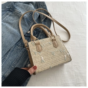 Détail de broderie florale sur sac à main en paille beige avec lanières en cuir brun
