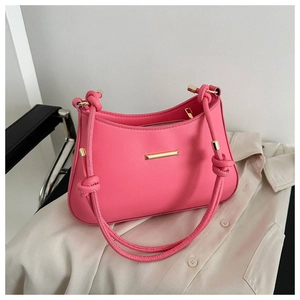 Detail of pink shoulder bag featuring gold metal bar and unique knotted strap design