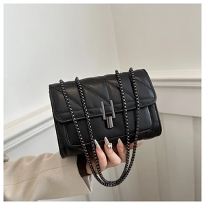 Gros plan d'un sac bandoulière matelassé noir avec chaîne gris foncé et fermoir métal