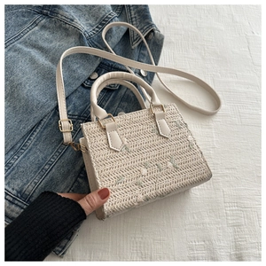 Détail de broderie florale sur un sac en paille avec ferrures dorées et bandoulière