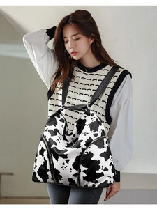 Fashionable cow print backpack with double zippers shown on an Asian model in a studio