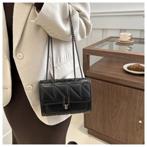 Détail du sac à bandoulière matelassé noir avec chaîne en métal et fermoir rotatif