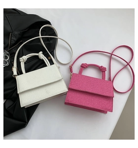 Detail view of woven texture crossbody bags in white and rose red with gold metal hardware