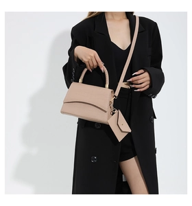 Détail du sac à main abricot avec texture crocodile, poignée tressée et mini pochette