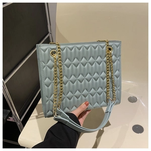 Detail of light blue quilted chain bag with elegant gold hardware and leather shoulder pad