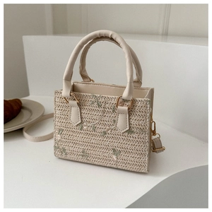 Détails d'un mini cabas en paille avec broderie florale et anses en cuir vegan