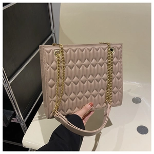 Detail of quilted leather tote bag with gold chain strap and apricot finish in hand
