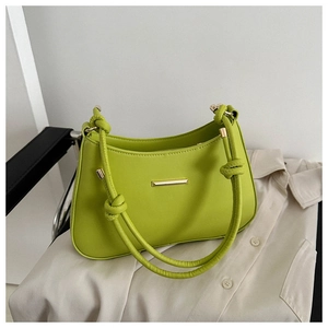 Detail of lime green shoulder bag with golden metal bar and knotted leather strap