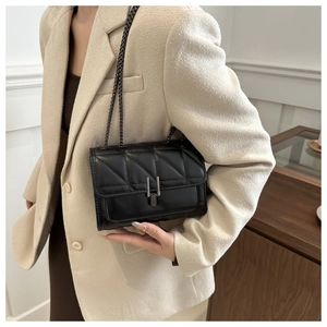 Détail d'un sac bandoulière en cuir noir matelassé avec chaîne et boucles en métal