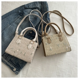 Vue détaillée de la texture du sac en paille avec broderie florale rose
