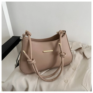 Detail of elegant beige leather shoulder bag with gold metal bar and twisted rope strap