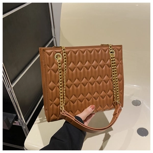 Detail of brown quilted tote bag with gold chain strap and elegant diamond pattern
