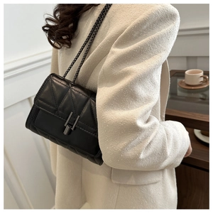 Détail du sac matelassé noir à chaîne avec boucle en U argentée sur veste en tweed
