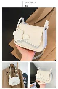 Dettaglio della borsa a tracolla bianco crema in pelle PU con ciondolo a fiore
