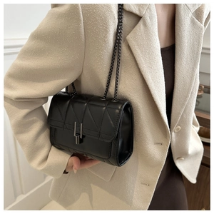 Détail d'un sac à bandoulière noir matelassé avec chaîne et fermoir métallique