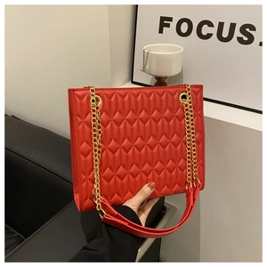 Detail of red quilted PU leather shoulder bag with golden chain strap and rectangular body