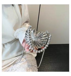 Macro detail of silver heart-shaped evening bag with pleated texture and beaded handle