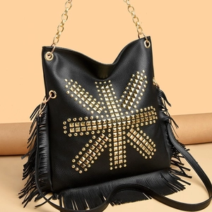 Black bucket bag with punk gold studs and long tassels on a minimalist background