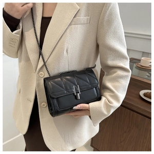 Détail du sac à bandoulière matelassé noir avec une chaîne et un fermoir en métal gris