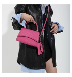 Détail du sac à main rose flamant à motif crocodile avec poignée tressée et pochette