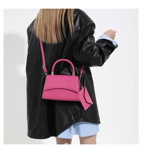 Vue détaillée d'un sac à main fuchsia à motif crocodile avec poignée tressée et d'or