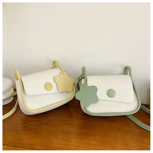Vista dettagliata di due borse a patta minimaliste in bianco-giallo e bianco-verde con ciondolo