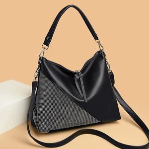 Close-up of black litchi leather shoulder bag with V-shaped silver rhinestone detailing