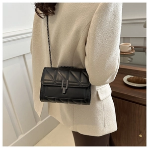 Vue arrière d'un mannequin portant un sac à bandoulière matelassé noir avec chaîne en métal