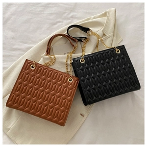 Detail of diamond quilted crossbody bag with gold chain strap and leather handle